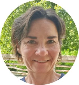 Frau mit kurzem braunem Haar lächelt vor grünem Hintergrund